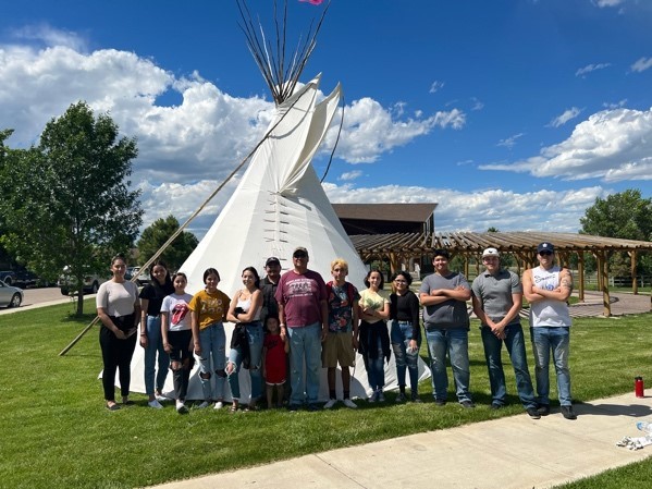 Students standing next to a tipi